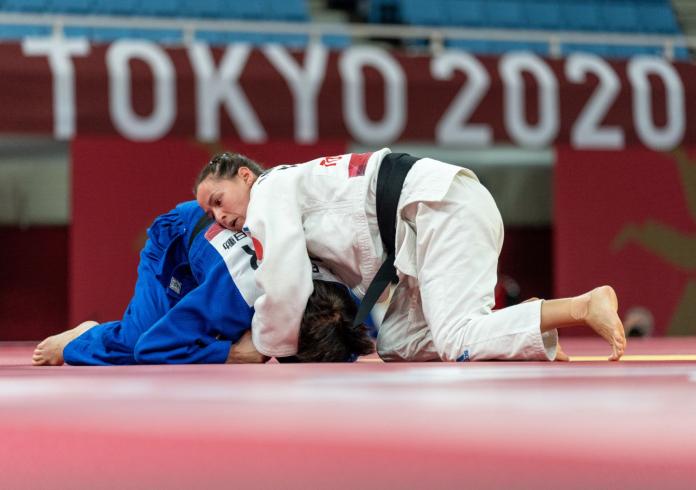 Two female athletes compete on a judo mat